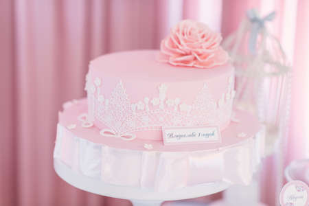 on a pink background festive pink cake with a big rose and white openworkの写真素材