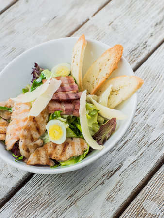 on a wooden base plate of Caesar salad with croutons and cheeseの写真素材