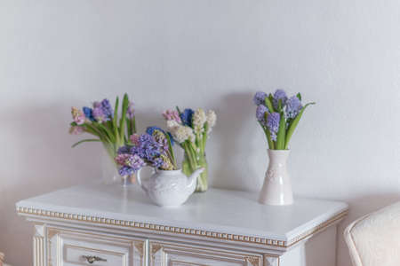 on a white table is a kettle and a vase with a bouquet of colored hyacinthsの写真素材