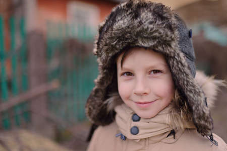 portrait of a young cheerful boy in winter fur hatの写真素材