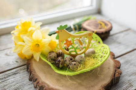 on a wooden table in different sizes bars nest with quail eggs and bouquet of yellow narcissus