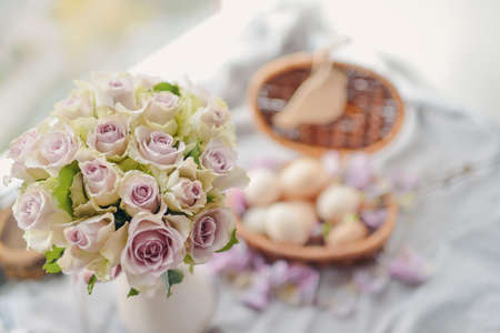 window wicker basket with eggs and a large bouquet of pink rosesの写真素材