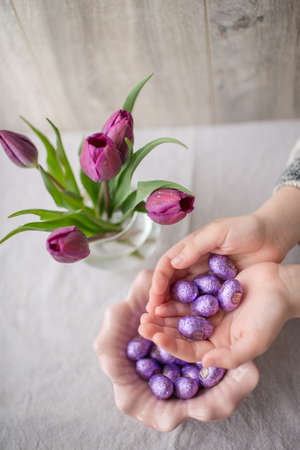in a glass vase bouquet of tulips and purple eggs in a small bowl in the hands ofの写真素材