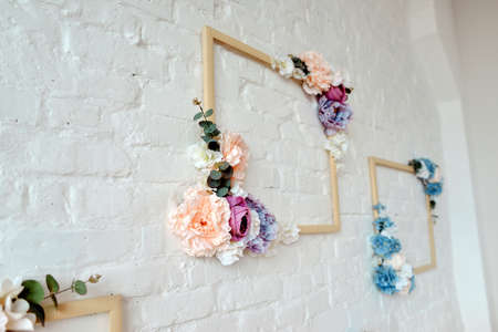 on a white brick wall wooden frame decorated with flowersの写真素材