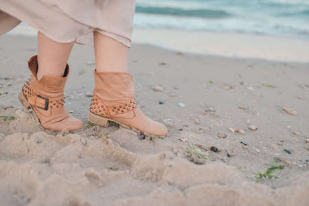 the sea on the sand female legs in brown suede bootsの写真素材