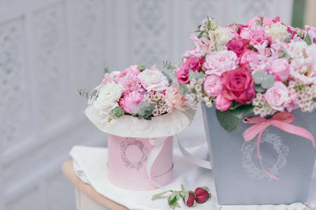 on a white table are boxes with a bouquet of roses and lilac