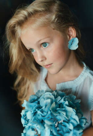 on a black background blond girl with blue eyes and hydrangeaの写真素材