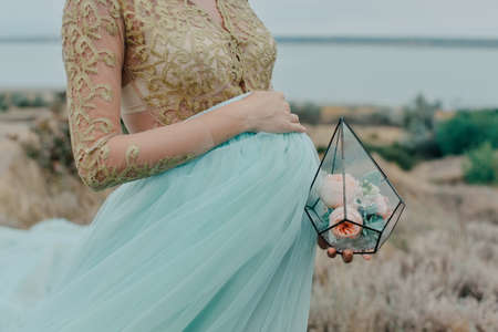 pregnant woman holding a glass box with rosesの写真素材