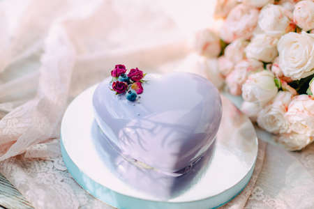 bouquet of pink roses and a cake with blue icing in the form of a heart with flowers