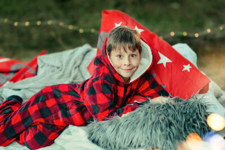 outdoors little boy lying in bed in red pajamas with toys and fruitの写真素材