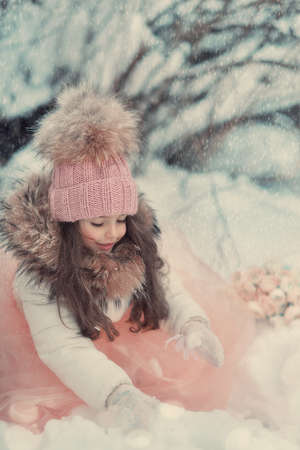 in the forest of snow in winter beautiful girl with long hair in a hatの写真素材