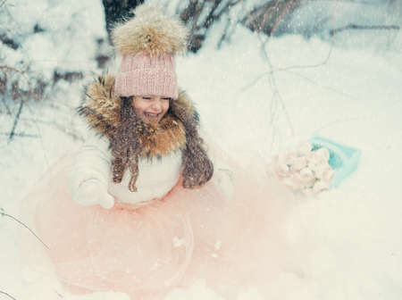 in the forest of snow in winter beautiful girl with long hair in a hatの写真素材