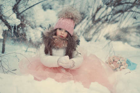 in the forest of snow in winter beautiful girl with long hair in a hatの写真素材