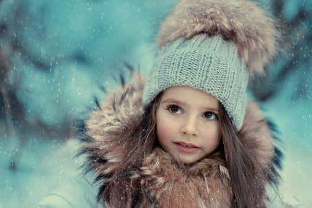 in the forest of snow in winter beautiful girl with long hair in a hatの写真素材