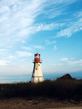 against the blue sky standing on the shore of a large, white stone lighthouse