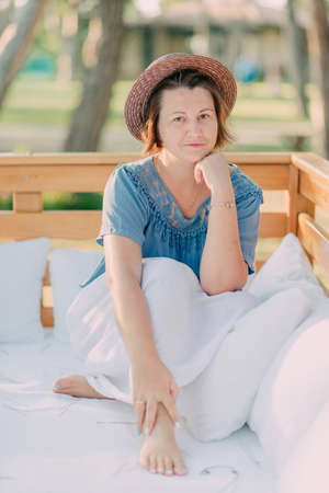 hot sunny day, a woman in a straw hat sitting on a wooden bench