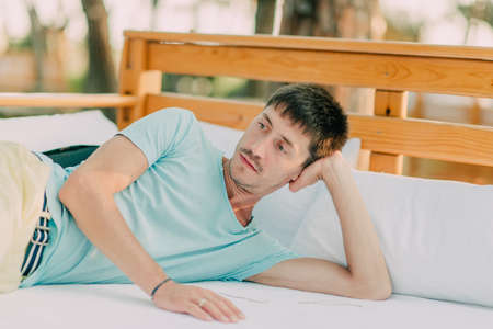 hot sunny day in a park on a wooden couch resting man