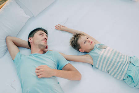 a large white bed are father and son in blue pajamas
