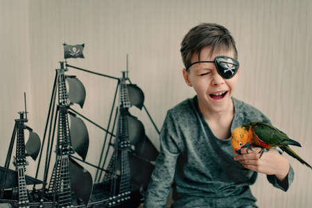 Black sailing ship and pirate boy playing with a large parrotの写真素材