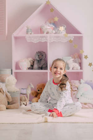 in the nursery pink home closet with toys, a cheerful girl in pajamasの写真素材