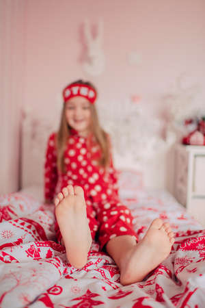 girl with long hair with a bandage to sleep in red pajamas sitting in bedの写真素材