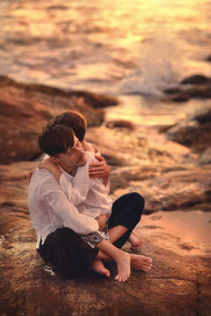 At the sea at sunset father hugs his sonの写真素材