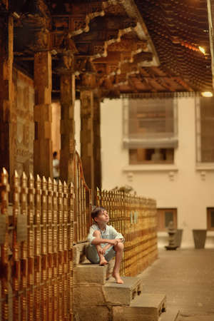 In the temple of a buddha's tooth, a small barefoot boy sits on the porchの写真素材