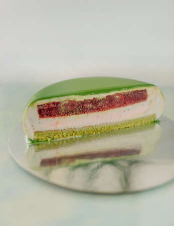 On the table a dish with half a lemon cake covered with green glazeの写真素材