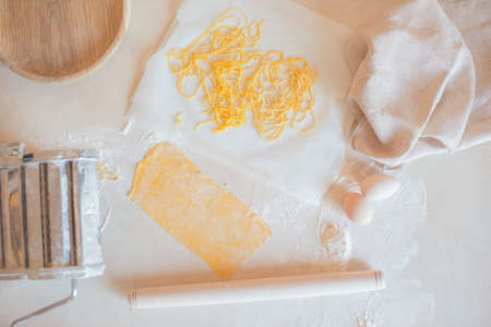 On a wooden table in flour home-made noodles and eggs. Wooden rolling pin