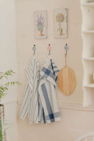 On the wall with paintings hang kitchen towels and a cutting boardの写真素材
