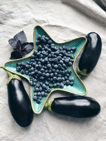 On the table a vase of star with blueberries and eggplant