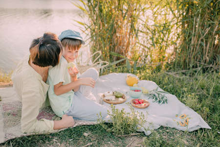 Mother and son on the river bank under the shining sunの写真素材