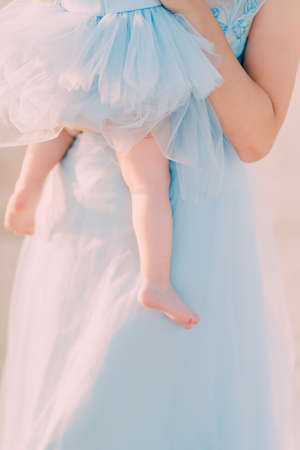a girl in a blue dress is holding a childの写真素材