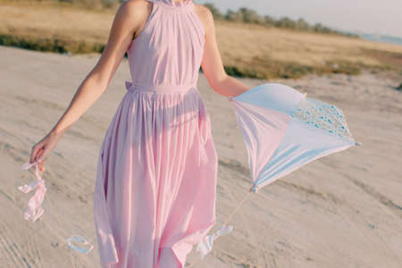 girl in pink dress launches kiteの写真素材