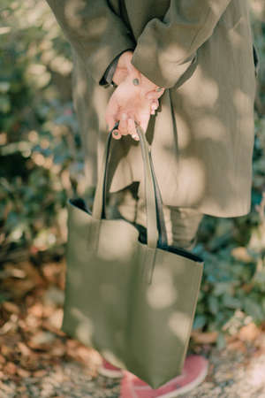 a green bag in the hands of a girl in a green coatの写真素材