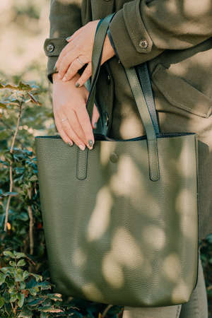a green bag in the hands of a girl in a green coatの写真素材