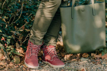 legs of a girl in red shoes with a green bagの写真素材