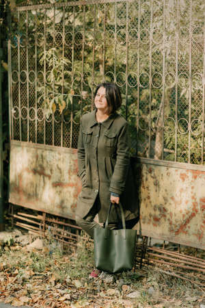 girl in green coat with green bag near the fenceの写真素材