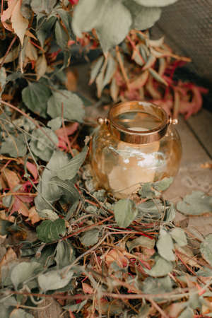 candlestick with white candles on the floor of leaves