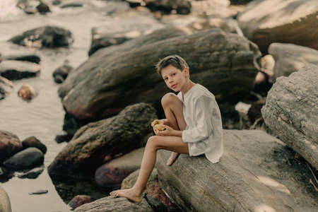 the boy is playing on the rocks on the ocean shoreの写真素材