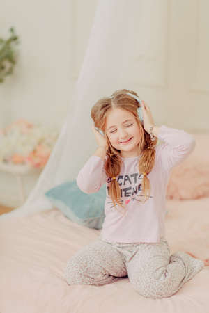 Redhead curly girl playing on the bedの写真素材