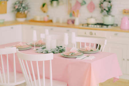 festive table setting with a beautiful bouquet, on a white plate a golden spoon and a fork and a...