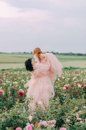 Girl in a pink dress on a field of rosesの写真素材