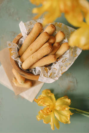 biscuit cookies in the form of sticks in a wooden plate with yellow flowers