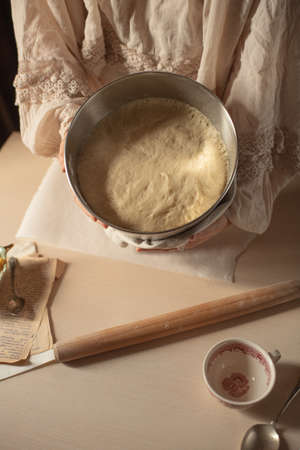 female hands knead the dough on a light background