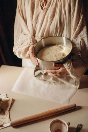 female hands knead the dough on a light backgroundの写真素材