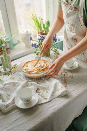 female hands cut an apple sweet pie, in light colors. sunny time in spring. food photoの写真素材