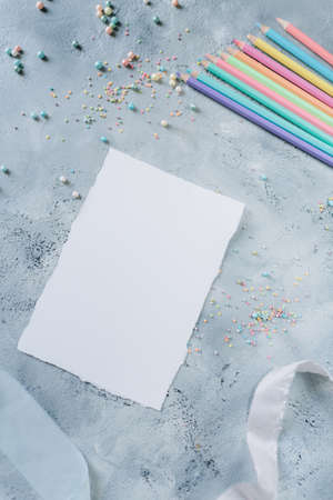 Mockup of a white sheet of paper with colored pencils on a concrete backgroundの写真素材