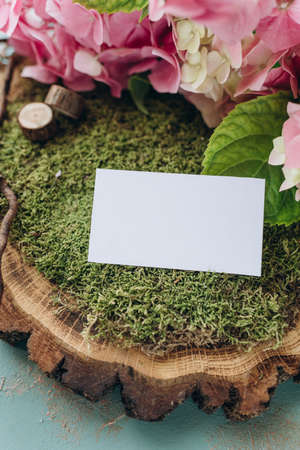 business card mockup in nature style, white paper on green moss and wood cutの写真素材