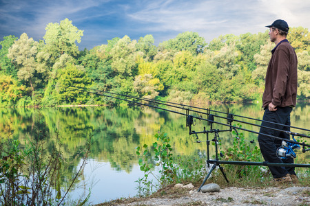 Fishing adventures. Fisherman and carp fishing gear. Fisherman near the carp fishing equipment on...